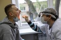 A medical worker takes swabs for the coronavirus test from a conscript during a medical checkup at a military conscription office in Moscow, Russia, Friday, May 22, 2020. The Russian military has launched a regular draft despite the coronavirus pandemic. (Kirill Zykov, Moscow News Agency photo via AP)