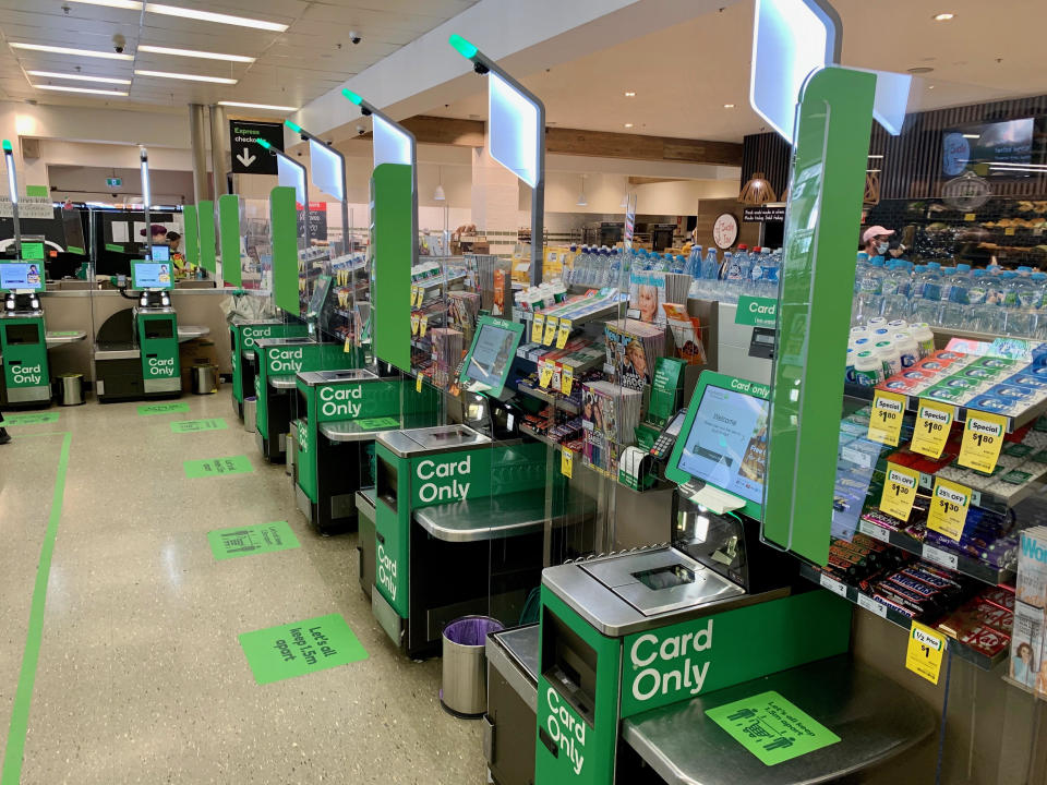 Picture of the new glass screens between self-serve checkouts at a Woolworths stall.