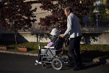 Eiichi Okubo (R), 71, pushes his wife Yumiko, 68, who has been suffering from dementia, in a wheel-chair at her care house in Tokyo, Japan, October 29, 2018. REUTERS/Toru Hanai