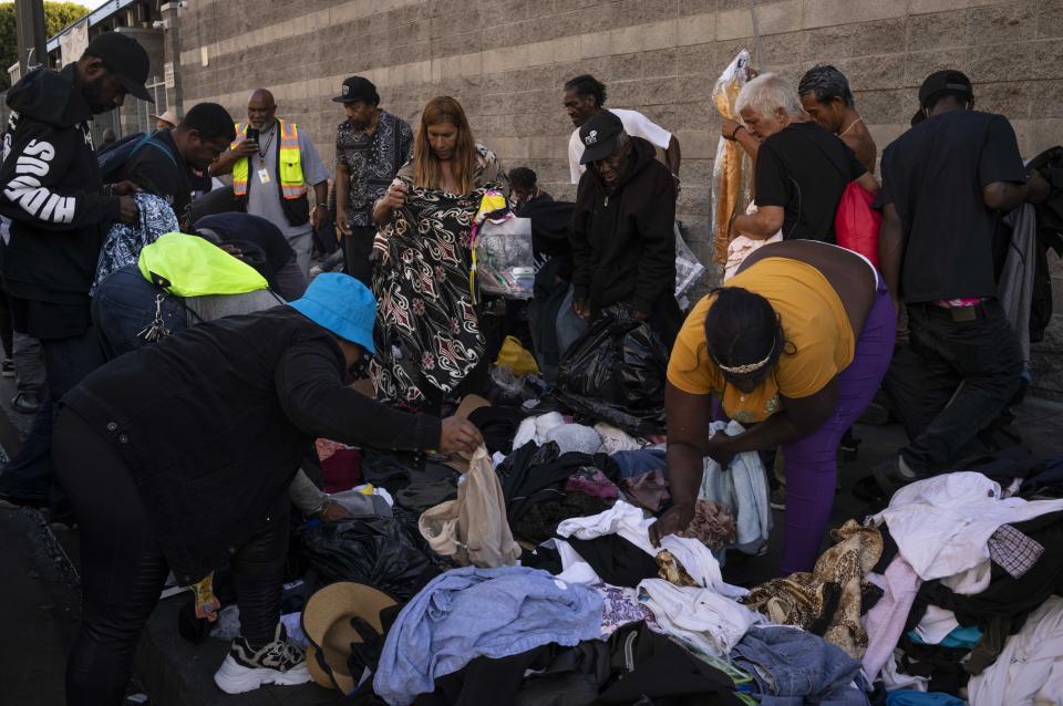 Homeless people gather around a pile of donated clothes to search for what they need in the Skid Row area of downtown Los Angeles, Thursday, Sept. 14, 2023. Billions of dollars have been spent on homelessness in the region, and an array of new programs are in place. But Mayor Karen Bass says it's possible that the number of homeless people will continue to increase, in part because of evictions and the end of pandemic aid that helped pay bills for lower-income households. (AP Photo/Jae C. Hong)