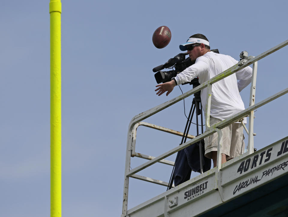 A member of the Carolina Panthers film crew tries to bat away a field goal-attempt during an NFL football practice at their training camp in Spartanburg, S.C., Sunday, July 27, 2014. (AP Photo/Chuck Burton)