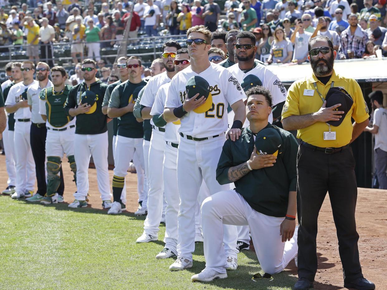 Oakland Athletics' Mark Canha (20) places his hand on the shoulder of Bruce Maxwell as Maxwell takes a knee during the national anthem prior to a baseball game against the Texas Rangers: AP