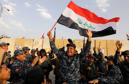 FILE PHOTO: A member of Iraqi Federal Police waves an Iraqi flag as they celebrate victory of military operations against the Islamic State militants in West Mosul, Iraq July 2, 2017. REUTERS/Erik De Castro/File Photo