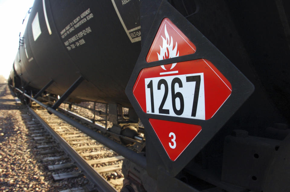 FILE - This Nov. 6, 2013 file photo shows a warning placard on a tank car carrying crude oil near a loading terminal in Trenton, N.D. The Trump administration vastly understated the potential benefits of installing more advanced brakes on trains that haul explosive fuels when it cancelled a requirement for railroads to begin using the equipment. A government analysis used by the administration to justify the cancellation omitted up to $117 million in potential reduced damages from using electronic brakes. Department of Transportation officials acknowledged the error after it was discovered by The Associated Press during a review of federal documents but said it would not have changed their decision. (AP Photo/Matthew Brown, File)