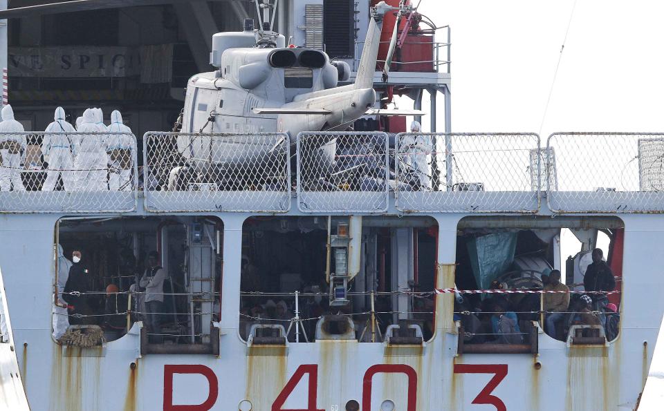 Migrants sit on the Italian Navy patrol ship Spica, as they arrive at the Sicilian harbour of Pozzallo