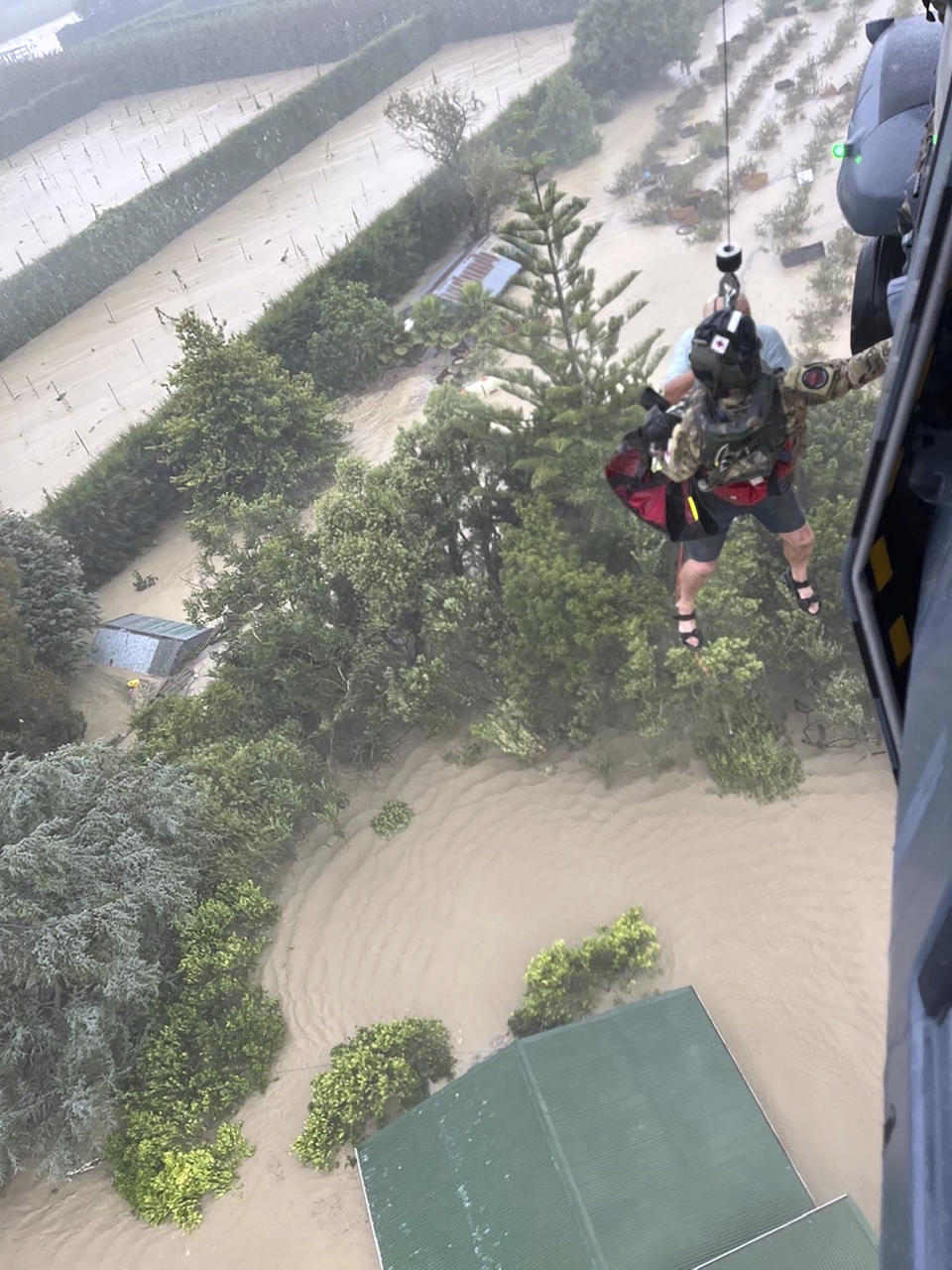 In this image released by the New Zealand Defense Force on Wednesday, Feb. 15, 2023, a person is winched from a rooftop of a home to safety by helicopter in the Esk Valley, near Napier, New Zealand. The New Zealand government declared a national state of emergency Tuesday after Cyclone Gabrielle battered the country's north in what officials described as the nation's most severe weather event in years. (New Zealand Defense Force via AP)