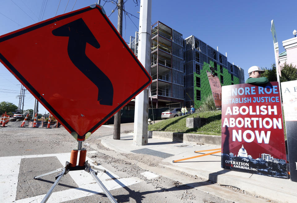 Abortion opponents stand outside the Jackson Women's Health Organization clinic, right, while construction on a hotel, background, continues in Jackson, Miss., Wednesday, April 10, 2019. The clinic is the only medical facility that performs abortions in the state. The state legislature recently passed a law that would ban most abortions after a fetal heartbeat is detected, meaning as early as six weeks. (AP Photo/Rogelio V. Solis)