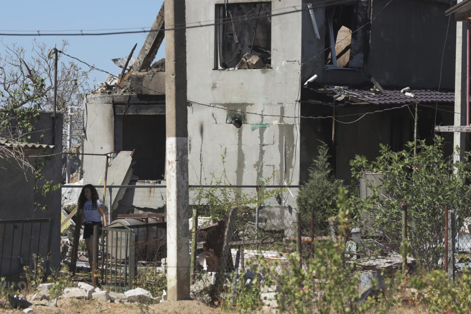 A woman walks in a yard of a apartment building destroyed by Russian shelling on the outskirts of Odesa, Ukraine, Tuesday, July 26, 2022. (AP Photo/Michael Shtekel)