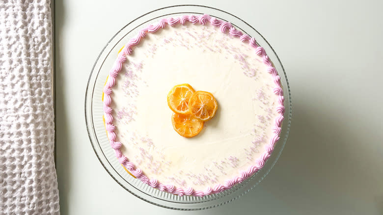 Bright and sunny lemon lavender cake with decorative buttercream border, lavender sprinkles, and cadied lemon wheels