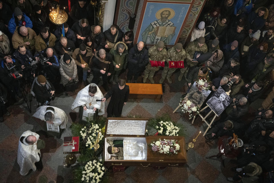 People pay their respects at the coffin of Ukrainian serviceman and famous Ukrainian poet Maksym Kryvtsov, who was killed in a battle with the Russian troops, during the funeral ceremony in St. Michael Cathedral in Kyiv, Ukraine, Thursday, Jan. 11, 2024. (AP Photo/Efrem Lukatsky)