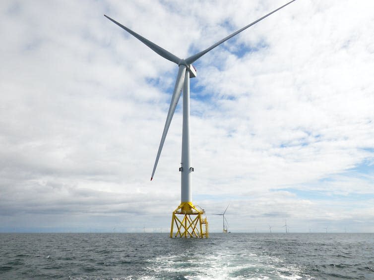 Une Éolienne Sur Une Plate-Forme Jaune Dans L'Océan.