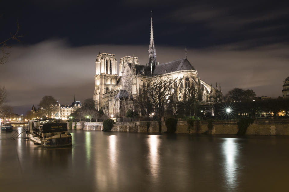 (FILES) In this file photo taken on January 29, 2018 A picture taken on the night of January 28, 2018 in Paris shows the flooded banks of the Seine river near Notre-Dame Cathedral. Several graves, including a lead sarcophagus probably dating from the 14th century, were discovered during an archaeological excavation prior to the reconstruction of the spire of Notre-Dame Cathedral in Paris, according with the French Ministry of Culture. / AFP / JOEL SAGET