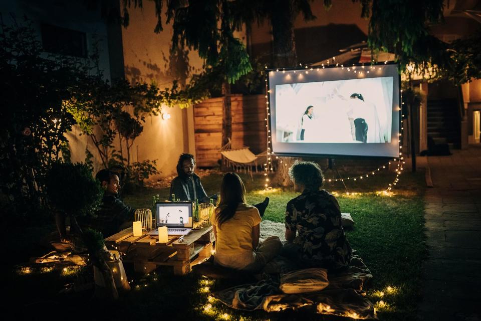 friends watching movie on the video projector in the backyard garden