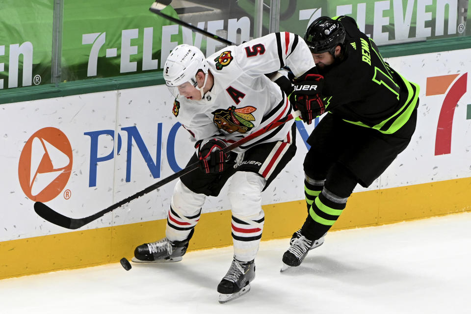 Dallas Stars left wing Jamie Benn (14) goes after the puck with Chicago Blackhawks defenseman Connor Murphy (5) along the boards during the second period of an NHL hockey game in Dallas, Thursday, March 11, 2021. (AP Photo/Matt Strasen)