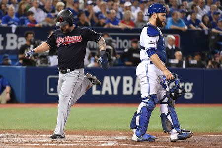 Oct 17, 2016; Toronto, Ontario, CAN; Cleveland Indians first baseman Mike Napoli (left) scores on a RBI-single by third baseman Jose Ramirez (not pictured) against Toronto Blue Jays catcher Russell Martin (right) during the sixth inning in game three of the 2016 ALCS playoff baseball series at Rogers Centre. Mandatory Credit: Nick Turchiaro-USA TODAY Sports
