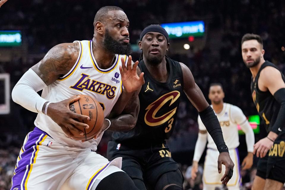 Lakers forward LeBron James, left, is fouled by Cavaliers guard Caris LeVert on a first-half drive to the basket, Saturday, Nov. 25, 2023, in Cleveland.