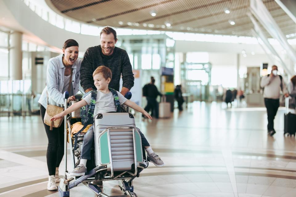 Mother, father and son pushing luggage cart as they travel through airport