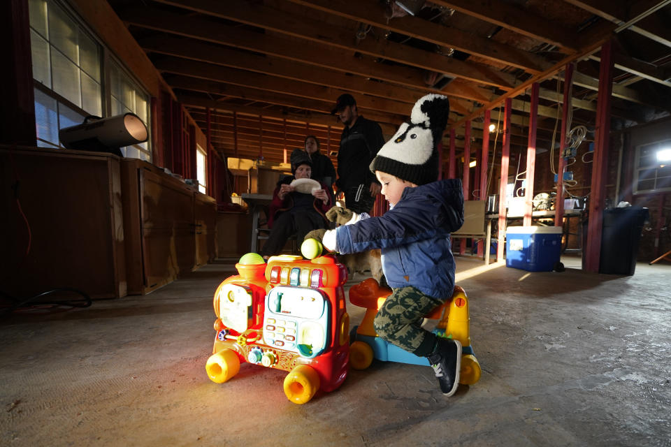 One-year-old Ricky Trahan plays on a Christmas toy on Christmas Eve inside the gutted Unson family home, in the aftermath of Hurricane Laura and Hurricane Delta, in Lake Charles, La., Thursday, Dec. 24, 2020. The extended family is living in tents and campers on the property, having all lost their homes to the storms. (AP Photo/Gerald Herbert)