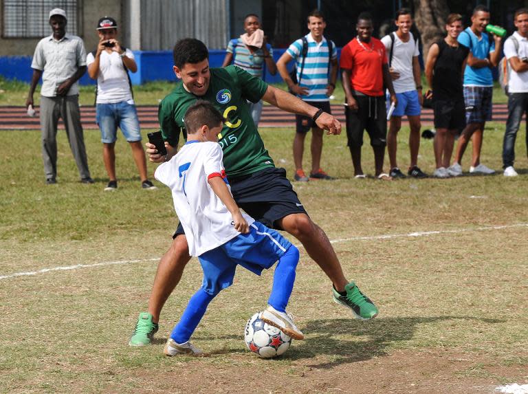 A US football team New York Cosmos' player tries to take the ball away from a child on a Cuban football team on June 1, 2015 in Havana