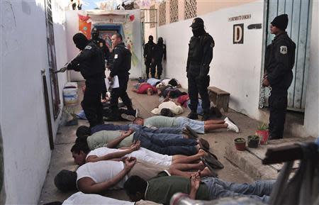 Inmates lie on the ground as riot policemen keep watch after a shooting in the Tuxpan prison in Iguala, in the Mexican State of Guerrero January 3, 2014. REUTERS/Jesus Solano