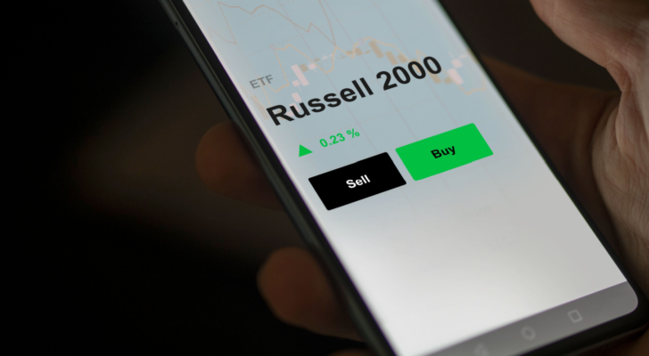 An investor's analyzing the russell 2000 etf fund on a screen. A phone shows the prices of Russell 2000. russell 2000 stocks