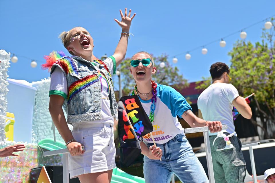 Jojo Siwa and Kylie Prew smile in rainbow outfits during a Pride parade