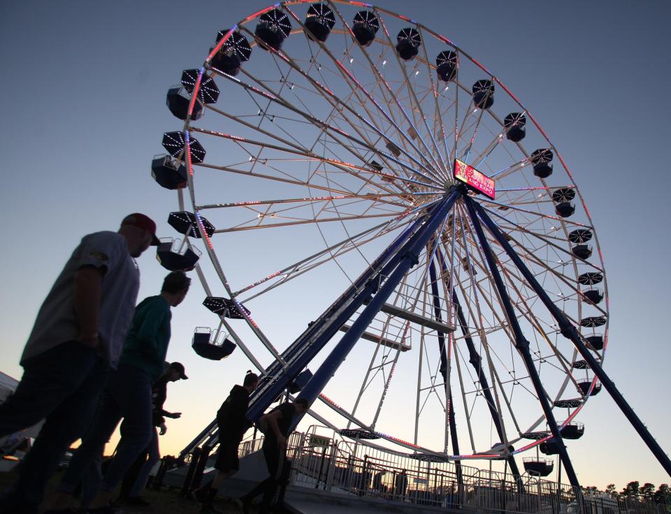 People walk past the Ferris wheel during the Cape Fear Fair & Expo in 2018.