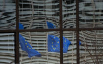 European Union flags are reflected in a window of the European Council in Brussels, Saturday, Dec. 19, 2020. The European Union and the United Kingdom were starting a "last attempt" to clinch a post-Brexit trade deal, with EU fishing rights in British waters the most notable remaining obstacle to avoid a chaotic and costly changeover on New Year. (AP Photo/Virginia Mayo)