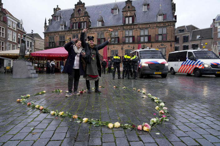 Two women flash V-signs after laying down roses in the form of a heart as police patrol the city center where a demonstration against COVID-19 restrictions and lockdown was banned in Nijmegen, eastern Netherlands, Sunday, Nov. 28, 2021. (AP Photo/Peter Dejong)