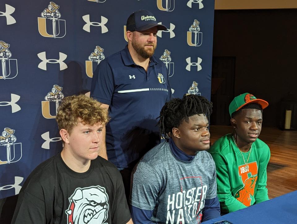 From left, University Christian offensive lineman Noah Clark (McPherson College), edge rusher Desirrio Riles (Indiana) and running back Orel Gray (Florida A&M) are pictured with head football coach David Penland III (at rear) during National Signing Day ceremonies on February 1, 2023. [Clayton Freeman/Florida Times-Union]