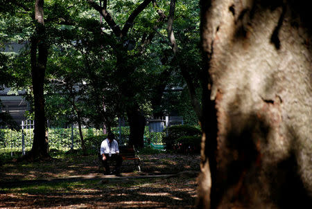 A man takes a rest under the shade of trees at a park nearby the construction site of the New National Stadium, the main stadium of the Tokyo 2020 Olympics and Paralympic in Tokyo, Japan July 24, 2018. REUTERS/Kim Kyung-Hoon