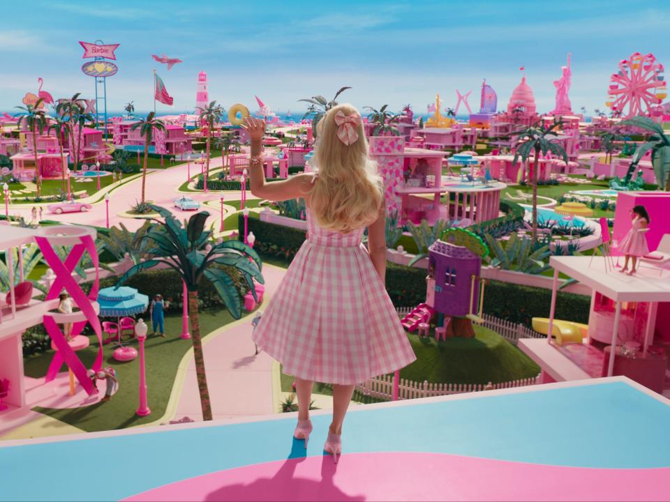 Margot Robbie's Barbie waving to Barbie Land citizens in "Barbie."