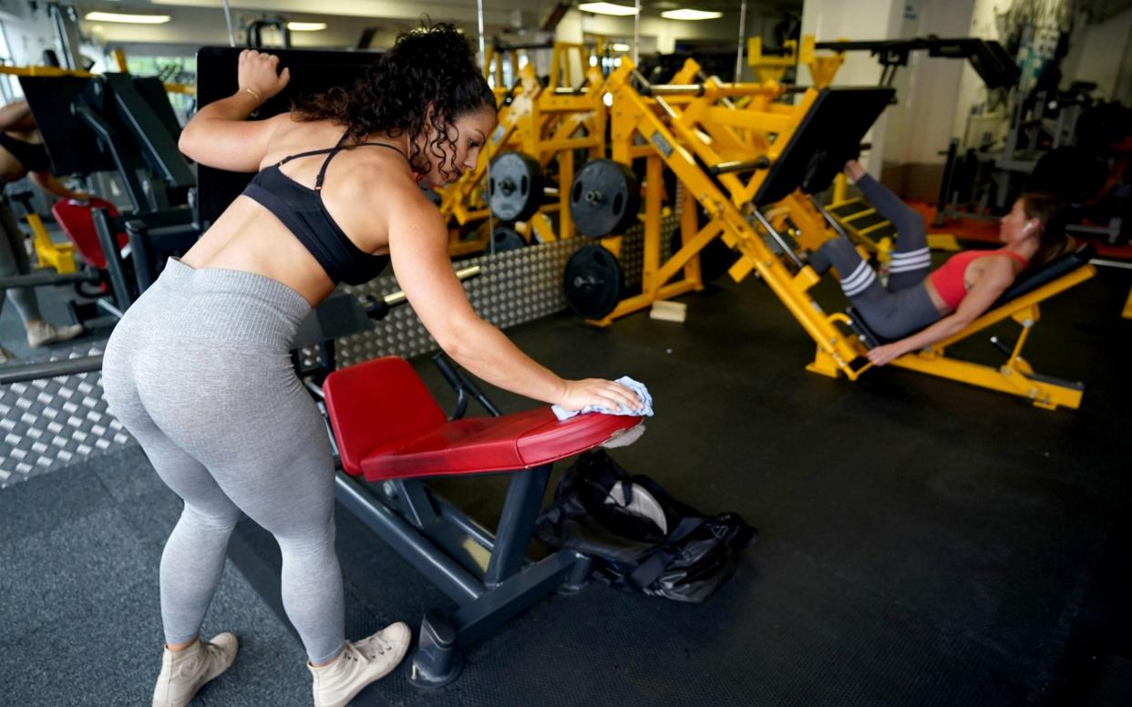 A gym member sanitises gym equipment after use at a branch of Ultimate Fitness - Morgan Harlow/PA
