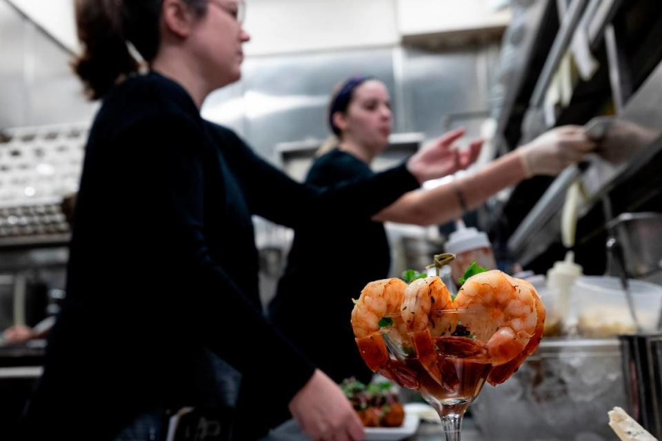 A shrimp cocktail is ready while Jessica Lagomarsine, left, and Vivian Fanjoy ready orders at Saluda’s Restaurant.