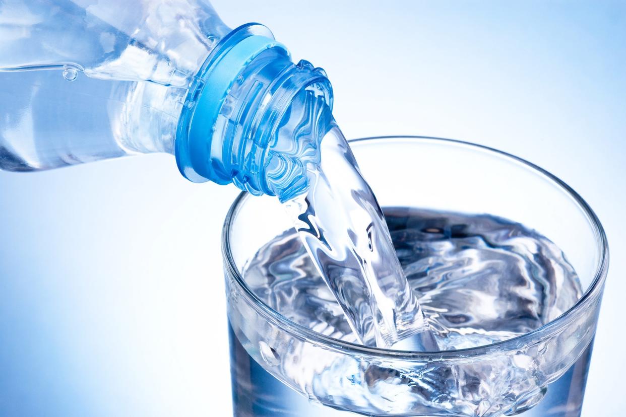 close-up pouring glass of water from a plastic bottle