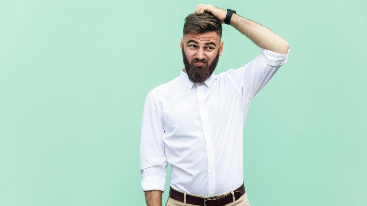  A man with a confused expression scratching his head. 