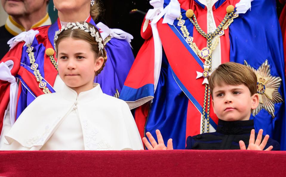 王室成員在白金漢宮陽台揮手致意，而路易伸出雙手左右揮，再展現淘氣一面。（AFP）