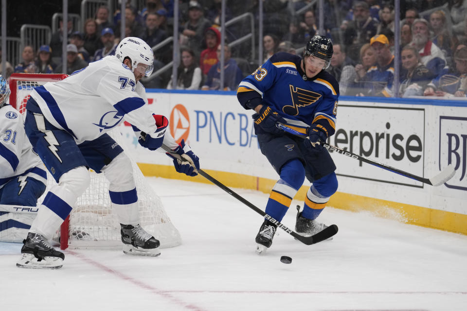 Tampa Bay Lightning's Victor Hedman (77) and St. Louis Blues' Jake Neighbours (63) chase after a loose puck during the second period of an NHL hockey game Tuesday, Nov. 14, 2023, in St. Louis. (AP Photo/Jeff Roberson)