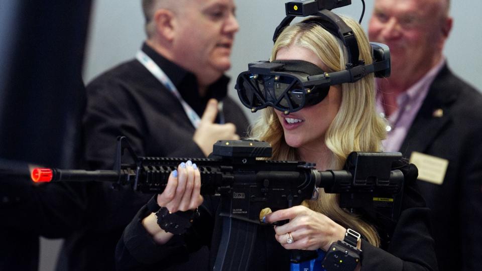 A woman engages with a shooting simulation at the General Dynamics Information Technology booth at the West 2024 conference in San Diego. (Colin Demarest/C4ISRNET)
