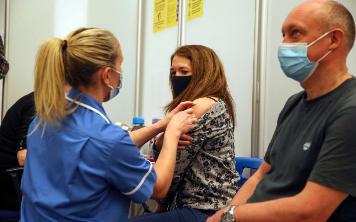 Husband and wife Caroline and Mark Nicolls receive an injection of the Moderna Covid-19 vaccine administered by nurse Amy Nash, at the Madejski Stadium in Reading, Berkshire - Steve Parsons 