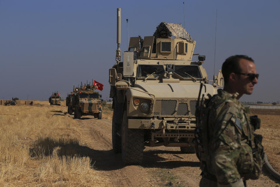 FILE - This Friday, Oct. 4, 2019 file photo, Turkish and American armored vehicles patrol as they conduct joint ground patrol in the so-called "safe zone" on the Syrian side of the border with Turkey, near the town of Tal Abyad, northeastern Syria. President Donald Trump’s announcement that U.S. troops in Syria would step aside to make way for a Turkish military operation against U.S.-allied Syrian Kurdish fighters unleashed a torrent of near unanimous criticism and warnings of immediate and long-term negative consequences. (AP Photo/Baderkhan Ahmad, File)