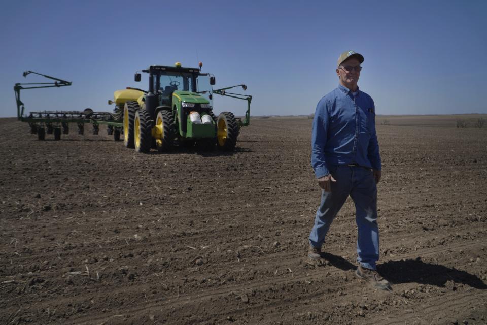 Todd Sanderson, who has seen how farming has changed during 42 seasons, takes a short break from planting corn to visit with his former pastor, on Wednesday, May 3, 2023, in Flandreau, S.D. Sanderson, 61, hopes a nephew will take over the farm from him eventually as his own children have decided to pursue other careers. (AP Photo/Jessie Wardarski)