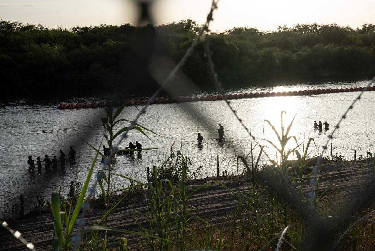 Migrants walk along the Rio Grande passed the recently installed buoys in Eagle Pass, Texas on July 29, 2023. As there is concertina wire installed along the Urbina’s property, migrants are told to walk to the end of the property. Many make that walk which can be difficult to do through slippery rocks in the water, the current and the inclined river bank, while some find spots through the concertina wire and manage to get through.
Verónica G. Cárdenas for The Texas Tribune