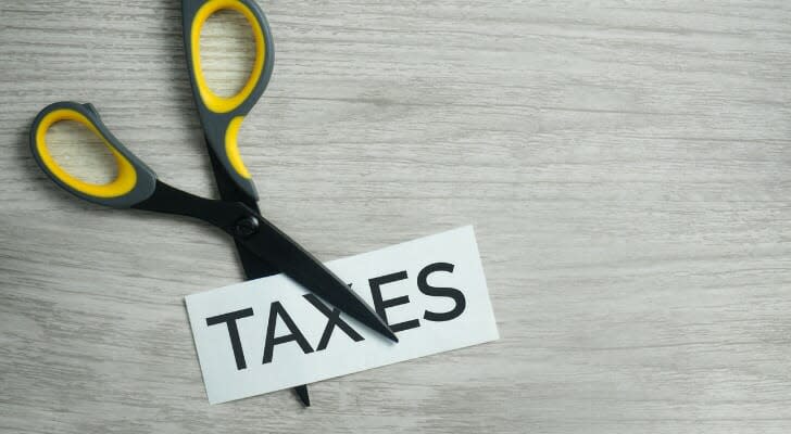 Scissors cutting a piece of paper with "TAXES" written on it