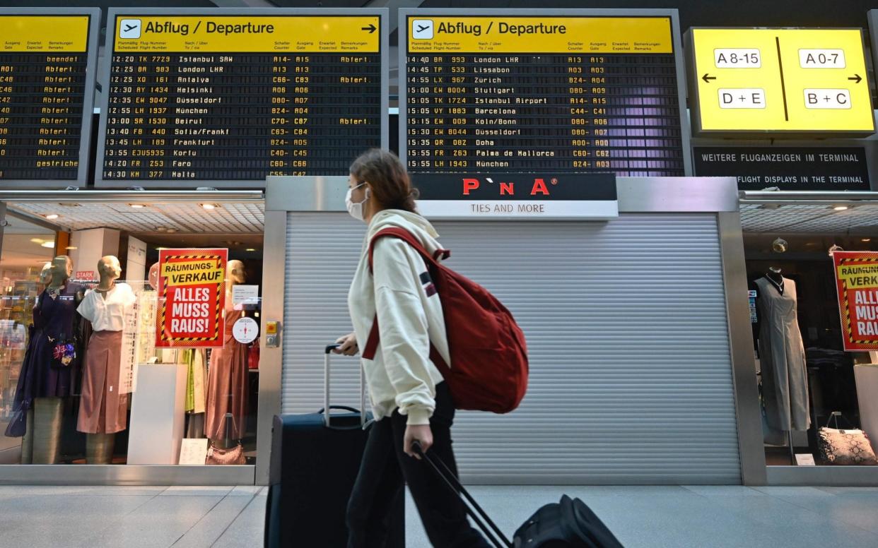 A passenger wears a face mask in an airport - John Macdougall/AFP