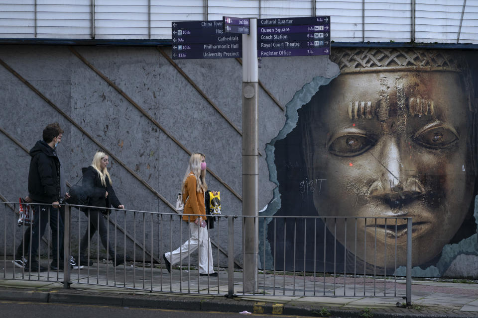 People walk in Liverpool, England, Monday Oct. 12, 2020. The British government has carved England into three tiers of risk in a bid to slow the spread of a resurgent coronavirus. The northern city of Liverpool is in the highest category and will close pubs, gyms and betting shops. (AP Photo/Jon Super)