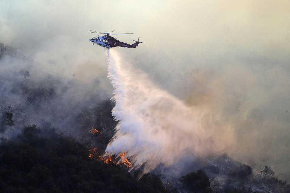 A helicopter drops water as the Getty fire burns on Mandeville Canyon Monday, Oct. 28, 2019, in Los Angeles. (AP Photo/Marcio Jose Sanchez)