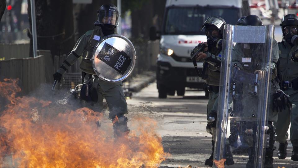 Ein Molotow-Cocktail geht vor Polizisten in Flammen auf.