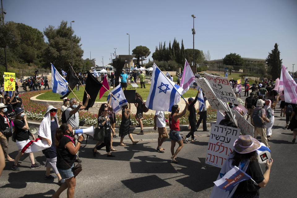 Israeli protesters wave flags and chant slogans during a demonstration against a proposed measure to curtail public demonstrations during the current nationwide lockdown due to the coronavirus pandemic, in front of the Knesset, Israel's parliament in Jerusalem, Tuesday, Sept. 29, 2020. (AP Photo/Sebastian Scheiner)