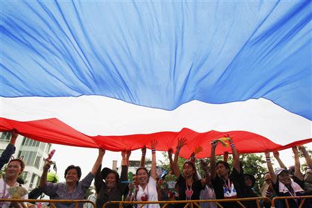 Anti-government protesters hold a giant national flag during a rally against the government-backed amnesty bill at the Democracy monument in central Bangkok November 24, 2013. REUTERS/Chaiwat Subprasom